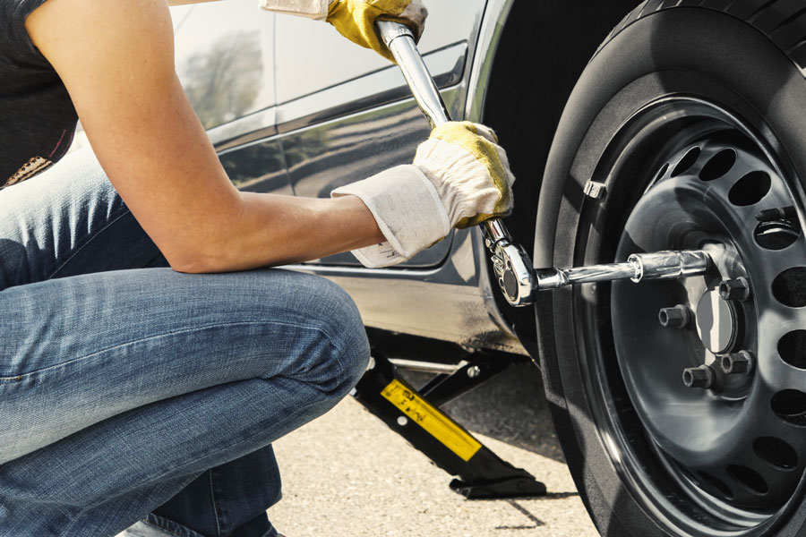 Woman changes tire with wrench