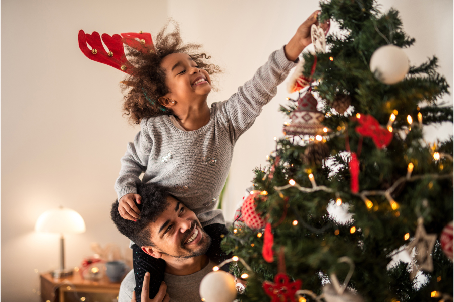father and daughter decorating holiday tree