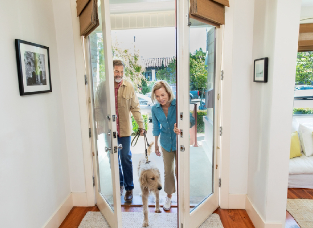 Older couple walking into home with their dog